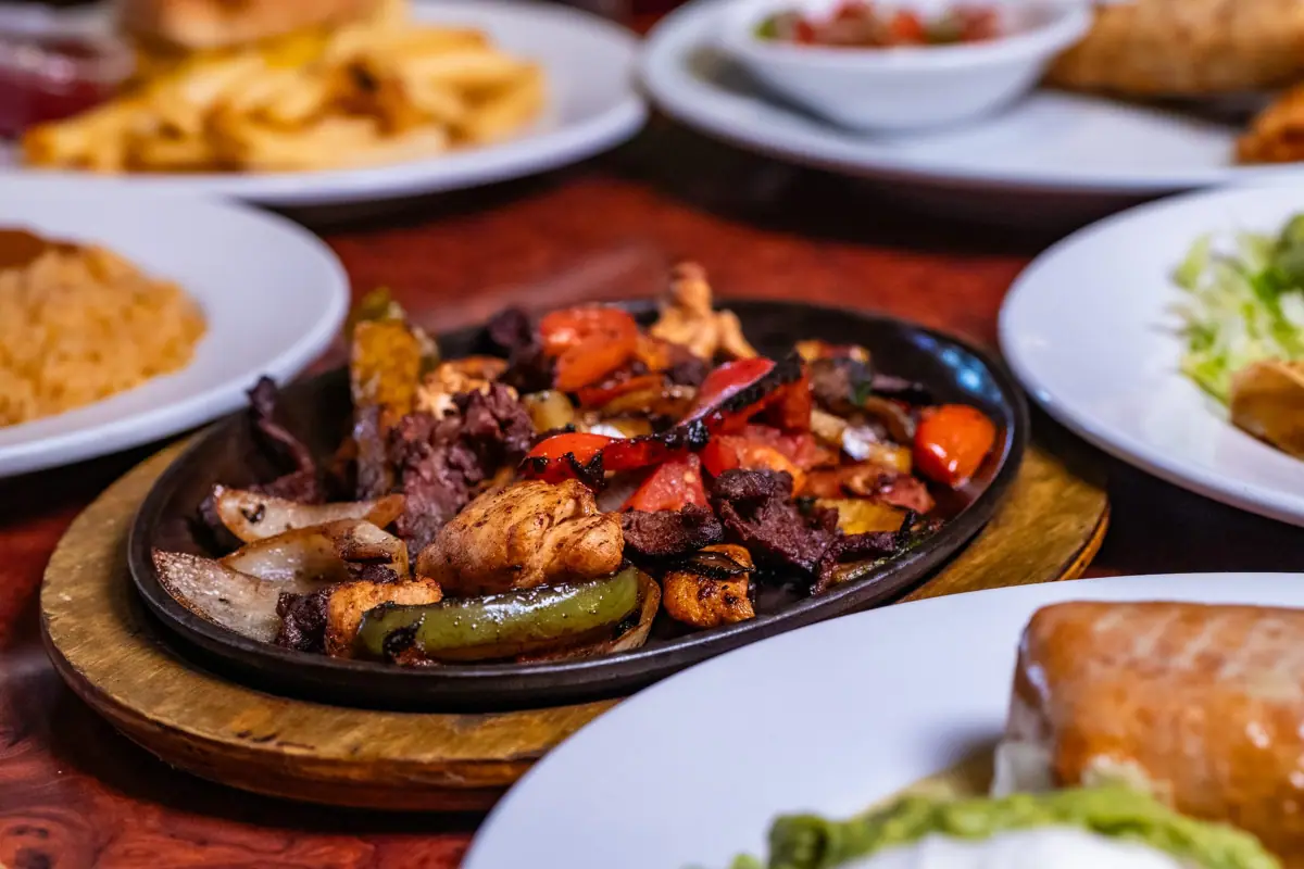 Fajitas with grilled steak, chicken, peppers and onions on a sizzling skillet