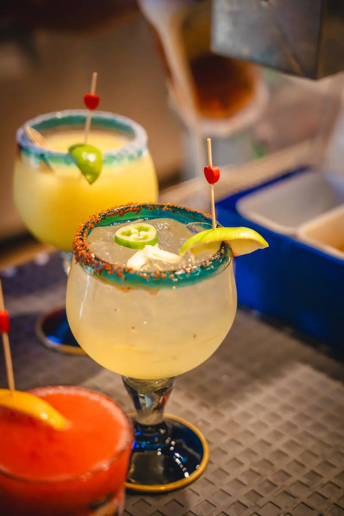 A lime margarita with a chili salt rim and sliced jalapeño