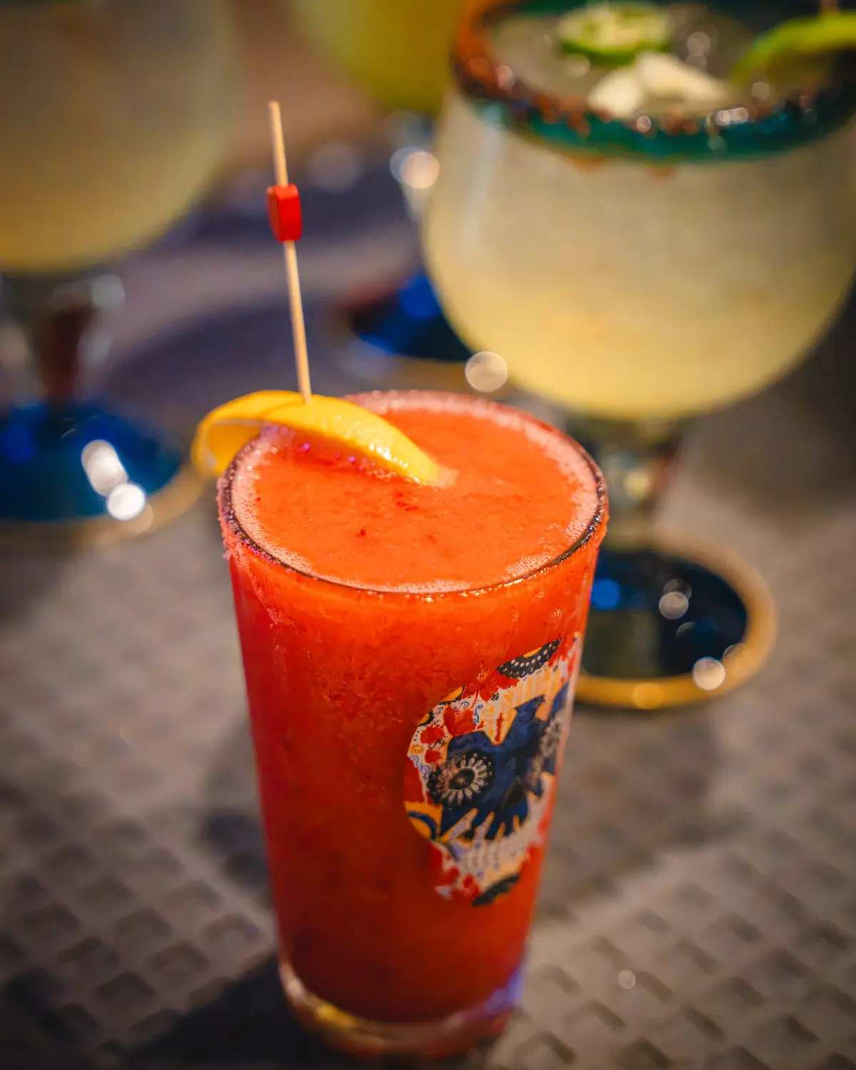 A frozen strawberry margarita with an orange slice